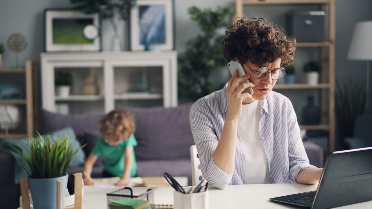 ragazza che tiene un cellulare in mano e tiene una conversazione telefonica davanti ad un pc