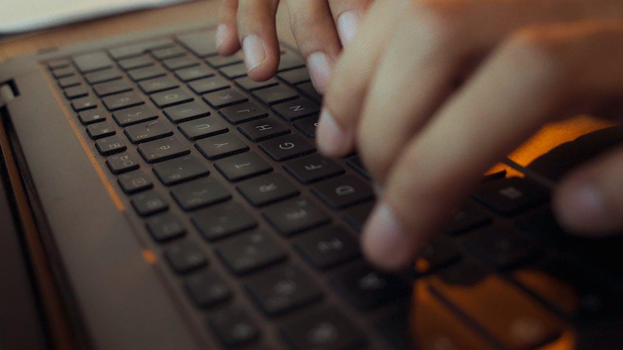 immagine di una persona che digita in una tastiera di un computer portatile; la foto mostra solo le dita ed un dettaglio della tastiera