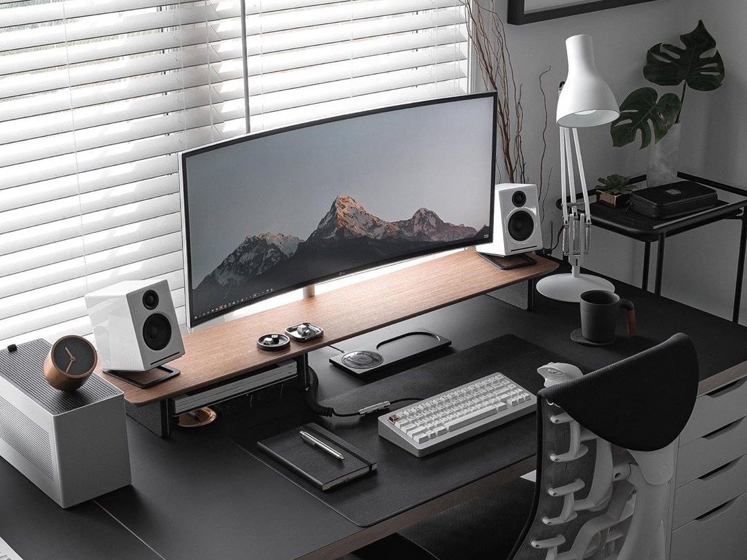 Workstation professionale in noleggio con monitor ultrawide, postazione ordinata e illuminazione naturale, ideale per uffici moderni e lavoro ad alte prestazioni